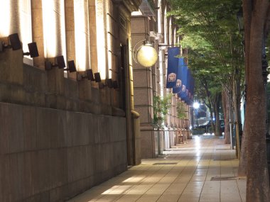 Şehir binalarının karanlık çöktükten sonra dramatik bir şekilde aydınlatıldığı bir sahne.