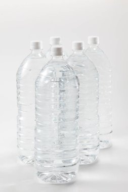 Beyaz zemin üzerinde su olan plastik şişeler..        