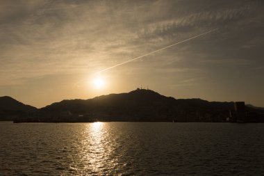 Deniz kıyısında siluetli dağlarla güzel bir gün batımı.