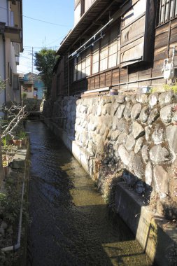 Dar dere eski taş duvar binalarının yanından akıyor güneş ışığı parlıyor