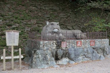 Dışarıda metal çitlerin arkasında duran büyük taş kaplan heykeli.