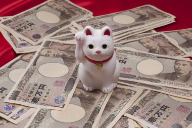 Japon yen banknotları ve Maneki-neko kedisi, şans ve zenginliği simgeliyor.