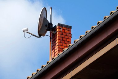 Uydu çanağı mavi gökyüzünün altındaki tuğla bacaya monte edildi.