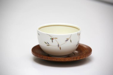 Dekoratif seramik çay fincanı ahşap fincan üzerinde dinleniyor.