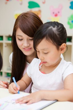 Genç Asyalı anne ve küçük tatlı kız birlikte çiziyorlar.