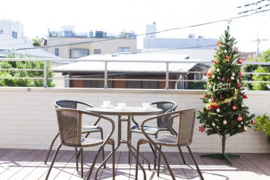 Sandalyeli sehpa ve terasta süslenmiş Noel ağacı.              