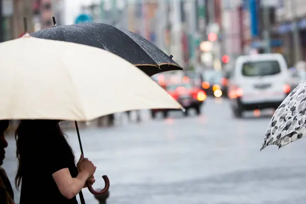 Büyük şehrin sokaklarında şemsiyeli insanlar var..                     