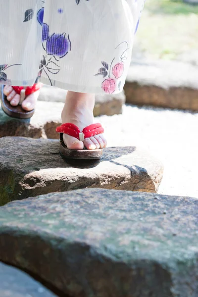 low section view of young woman wearing kimono and geta sandals in garden