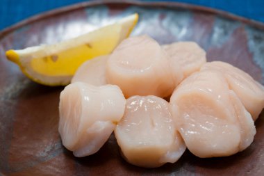 Tabağında limon dilimi olan çiğ deniz tarakları 