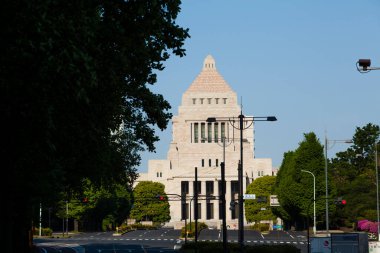 Gökyüzünün altında yeşil ağaçlarla çevrili tarihi hükümet binası