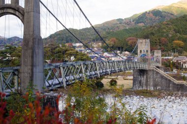 Küçük köy evleri yakınlarındaki nehirden geçen asma köprü.