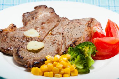 Beyaz tabakta nefis ızgara biftek ve sebze manzarası.                  