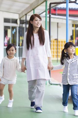 Japon kadın iki sevimli küçük kızla yürüyor ve el ele tutuşuyor. 