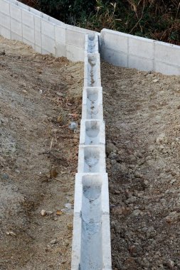 Beton bloklar toprak yamaçta düz istinat duvarı oluşturuyor.