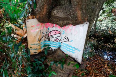 Ağaç dalları arasında yıpranmış yüzme uyarısı işareti