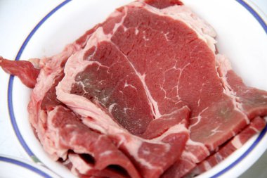 Tabaktaki taze çiğ bifteklerin yakın plan görüntüsü..