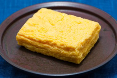 a square of food on a plate on a blue tablecloth