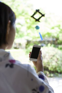 Kimono giyen genç Japon kadın akıllı telefon kullanıyor. 
