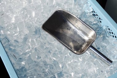 Plastik kovada buz küpleri ve metal kepçe.  