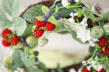 Güzel düğün süsü, beyaz çiçeklerin doğal çelengi, ahududu, yabanmersini ve yeşil yapraklar.