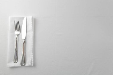 Gri arkaplanda çatal bıçak takımı ve peçete, kopyalama alanı, üst görünüm    