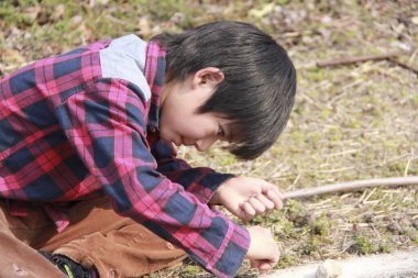 Genç Asyalı çocuk yerde oynuyor.