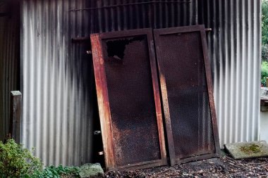 Yanmış ahşap kapı, bükülmüş metal duvara yaslanmış.