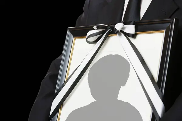 stock image Close-up view of person holding funeral frame with man silhouette 