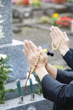 Bir erkek ve bir kadın, cenaze töreninde kalpten yakarışlarını Tanrı 'ya yöneltirken kutsal bir duayla gösterilir. 