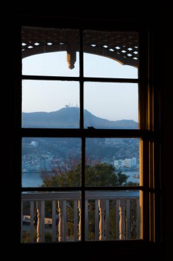Gün batımında tahta çerçeveli pencereden görünen dağ manzarası