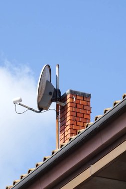 Uydu çanağı, mavi gökyüzüne karşı kırmızı tuğla bacanın üzerine monte edildi.