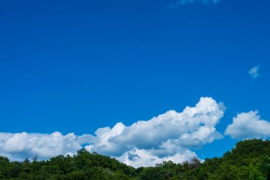 Mavi gökyüzü, bulutlar ve uzaktaki dağlar.