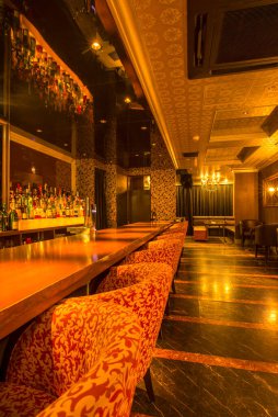 Lüks restoranın içi, rahat kırmızı sandalyelerle dolu.