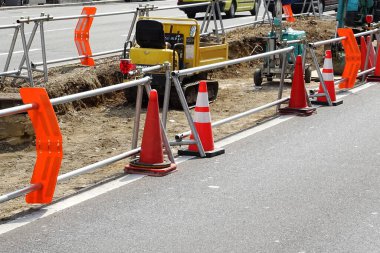 Turuncu koniler ve güvenlik bariyerleri gösteren inşaat alanı