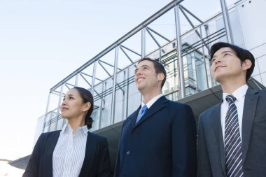 İş ekibi ofis binasının önünde duruyor.