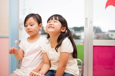 Diş fırçası tutarken gülümseyen iki genç kız.