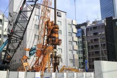 İnşaat alanı yakınlarda ağır makineler ve binalar gösteriyor.