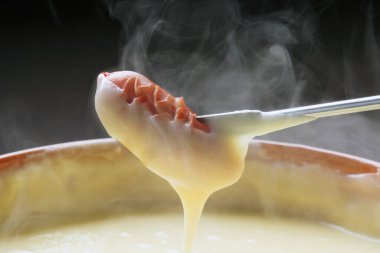 Erimiş peynirin içine sosis batırıyorum.