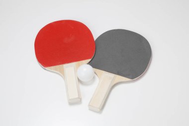 Gri arkaplanda iki pinpon raketi ve top, yakın çekim görünümü