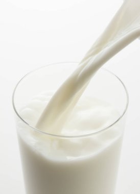 Bardağa bir bardak süt dökülüyor.