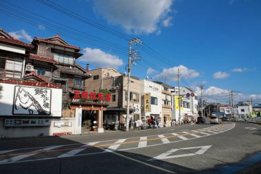 Parlak ticari tabelalar ve yoğun trafik bu aktif Japon caddesinin görünümünü tanımlar.
