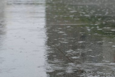 Islak şehir caddesinde yağmur damlaları ve su birikintileri