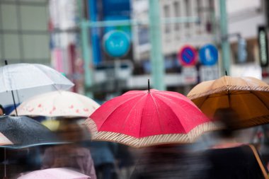 Şehir caddesinde yağmurda yürüyen şemsiyeli insanların bulanık görüntüsü                   
