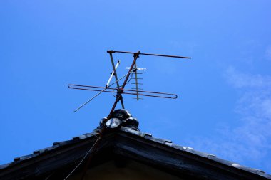 Metal anten açık mavi gökyüzüne karşı çatıya monte edildi