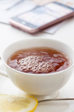 Bir bardak limon dilimli çay ve akıllı telefon.