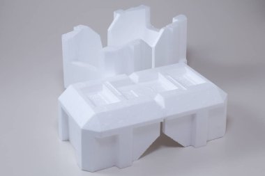 White molded styrofoam packaging resting against plain background surface