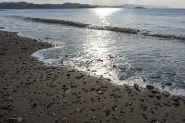 Akşamları deniz kıyısında gün batımında taşlarla