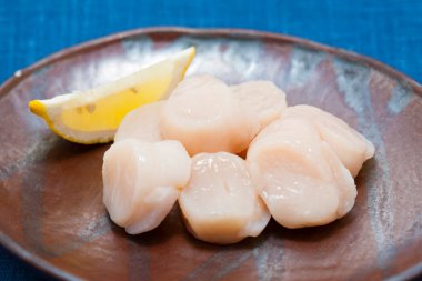 Tabağında limon dilimi olan çiğ deniz tarakları 