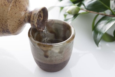 Japon sake 'sini şişeden killi fincana dök