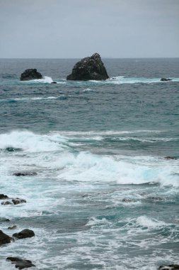 Uçurumları ve bulutlu bir günde dalgaları olan güzel deniz manzarası.    